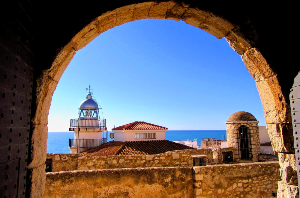 Stone arch frames lighthouse and sea view in Peñíscola