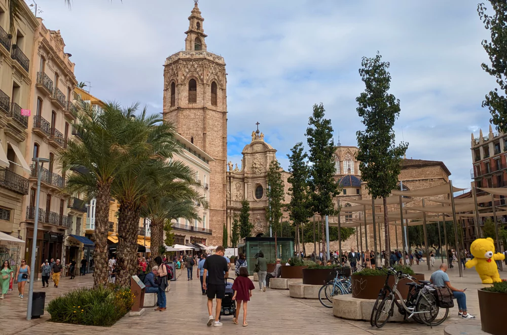 Plaza de la Reina in Valencia old town, with the Cathedral and Micalet tower dominating the square filled with palm trees and people