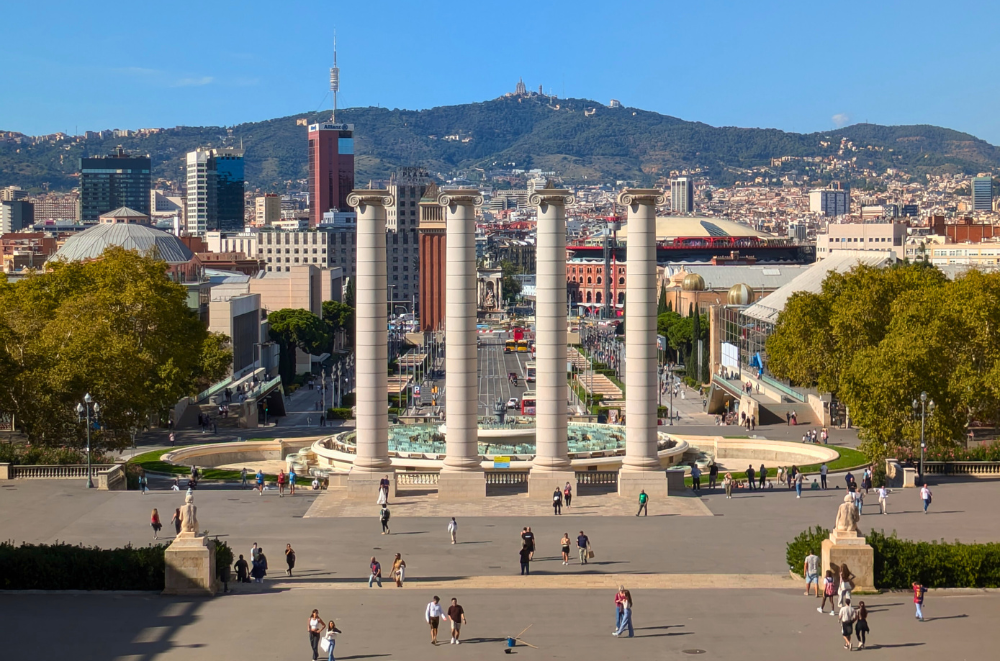 Panoramic view of Barcelona cityscape with iconic columns and Tibidabo mountain in the background