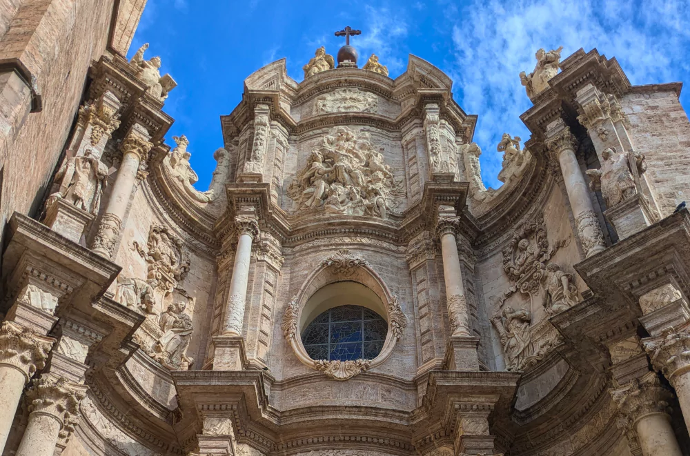 Valencia Cathedral's ornate baroque facade in Valencia old town, featuring detailed stone carvings, religious sculptures, and a central rose window