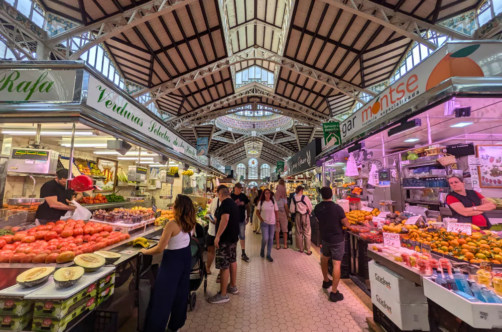 Interior of Central Market in Valencia old town, with its modernist architecture and busy fruit stalls under a soaring iron roof