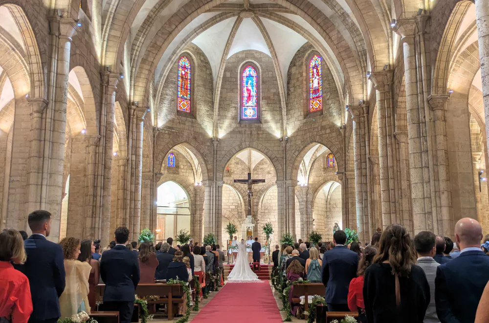 Interior of Church of San Juan del Hospital in Valencia old town during a wedding ceremony, showing Gothic arches and stained glass windows