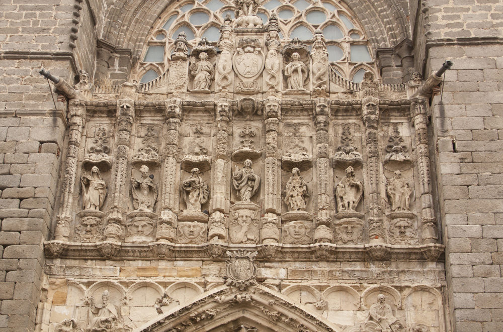 Ornate stone facade of the Ávila Cathedral with intricate carvings of religious figures, statues, and decorative elements